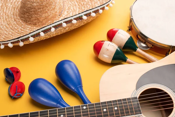 Instrumentos musicais e sombrero mexicano sobre fundo amarelo — Fotografia de Stock