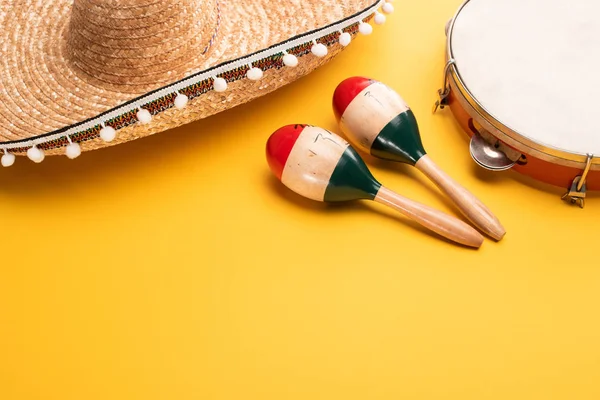 Maracas colorate in legno, tamburello e sombrero su sfondo giallo — Foto stock