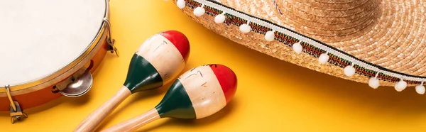 Tambourine, maracas and sombrero on yellow background, panoramic shot — Stock Photo