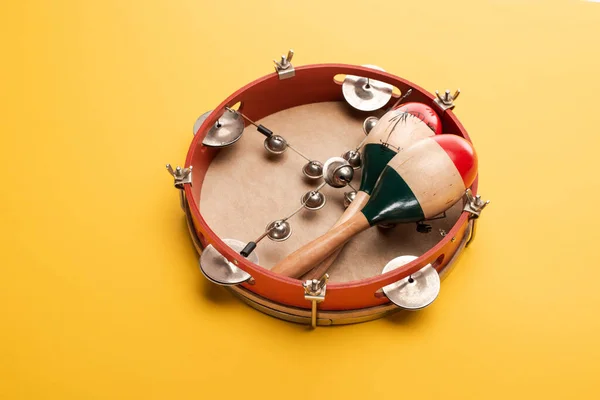 Wooden colorful maracas on tambourine on yellow background — Stock Photo