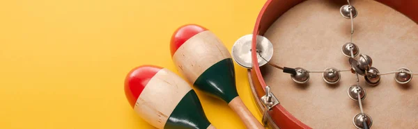 Close up view of tambourine near colorful maracas on yellow background, panoramic shot — Stock Photo