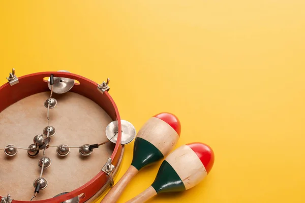 Tamburello vicino a maracas di legno colorato su sfondo giallo — Foto stock