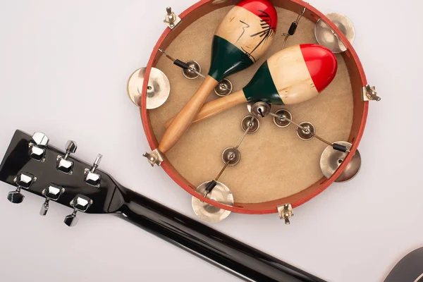 Vista superior de la guitarra acústica cerca de maracas de madera sobre pandereta sobre fondo blanco - foto de stock