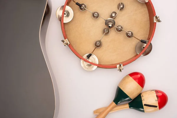 Top view of acoustic guitar near wooden maracas and tambourine on white — Stock Photo