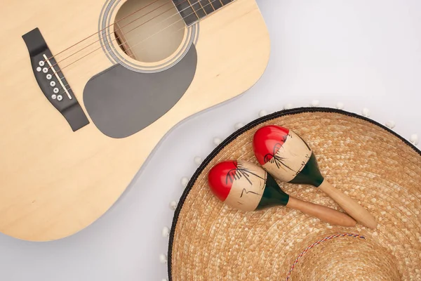 Вид зверху на акустичну гітару з дерев'яними маракасами на сомбреро на білому тлі — стокове фото