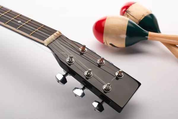 Focus selettivo della chitarra acustica vicino alle maracas di legno sul bianco — Foto stock