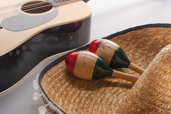 Nahaufnahme von hölzernen Maracas auf Sombrero und akustischer Gitarre auf weißem Hintergrund — Stockfoto