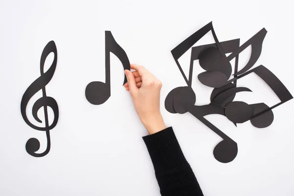 Cropped view of female hand with paper cut black music notes on white background — Stock Photo