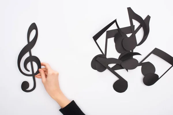 Vue partielle de la main féminine avec des notes de musique coupées en papier noir sur fond blanc — Photo de stock