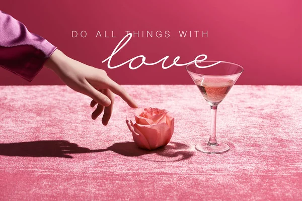 Cropped view of woman touching rose near glass with drink on velour cloth isolated on pink, do all thing with love illustration — Stock Photo