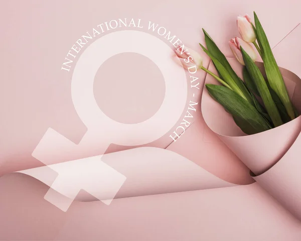 Top view of tulips wrapped in paper on pink background, international womens day illustration — Stock Photo