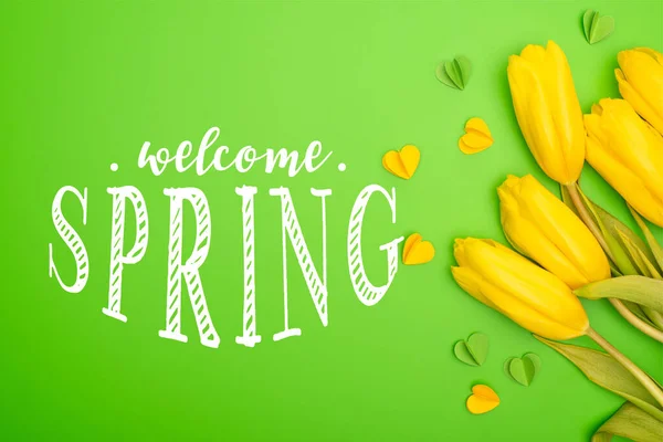 Top view of yellow tulips and decorative hearts on green, welcome spring illustration — Stock Photo
