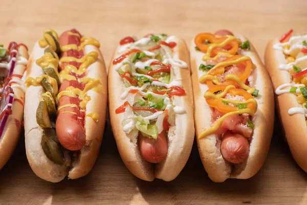 Fresh delicious hot dogs with sauces on wooden table — Stock Photo