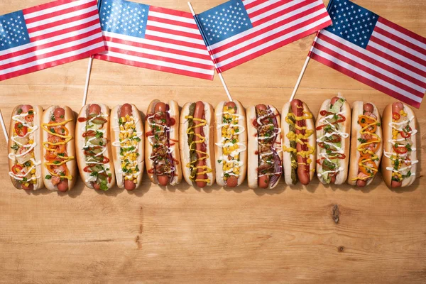 Top view of fresh delicious hot dogs and american flags on wooden table — Stock Photo
