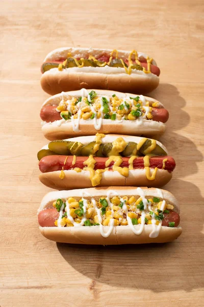 Delicious hot dogs with corn, green onion and pickles on wooden table — Stock Photo