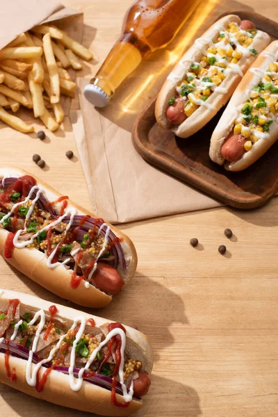 Leckere Hot Dogs neben Bier und Pommes auf Holztisch — Stockfoto