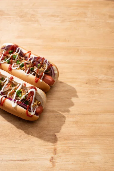 Deliciosos cachorros-quentes com cebola vermelha, bacon e mostarda Dijon na mesa de madeira — Fotografia de Stock