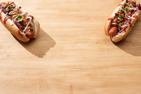 Deliciosos cachorros-quentes com cebola vermelha, bacon e mostarda Dijon na mesa de madeira — Fotografia de Stock