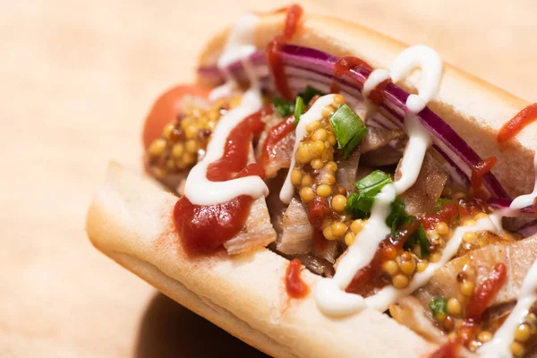 Nahaufnahme von köstlichem Hot Dog mit roten Zwiebeln, Speck und Dijon-Senf auf Holztisch — Stockfoto