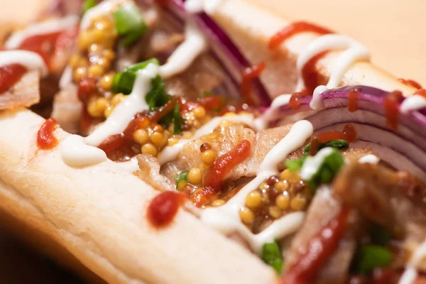 Close up view of delicious hot dog with red onion, bacon and Dijon mustard — Stock Photo