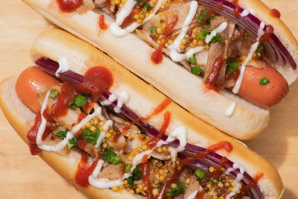 Vista superior de deliciosos cachorros-quentes com cebola vermelha, bacon e mostarda Dijon na mesa de madeira — Fotografia de Stock