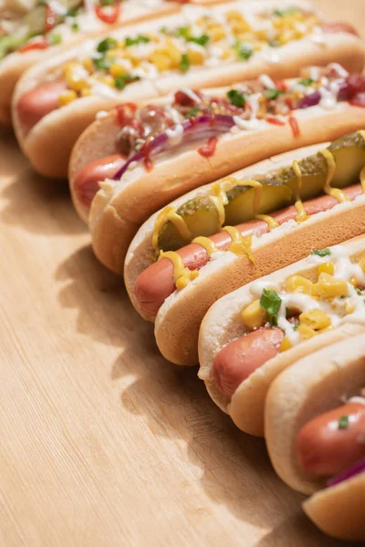 Selective focus of fresh various delicious hot dogs with vegetables and sauces on wooden table — Stock Photo