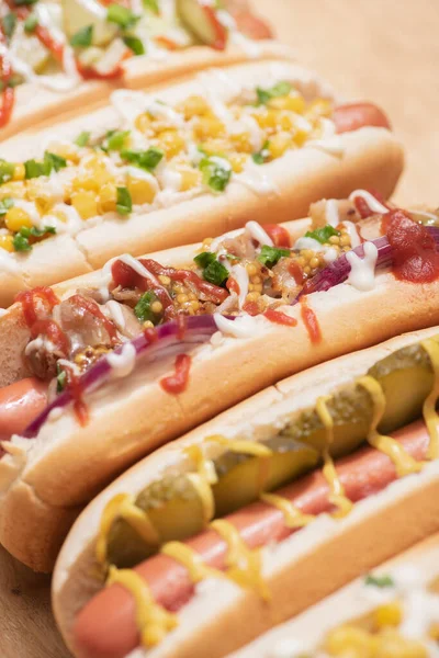 Selective focus of fresh various delicious hot dogs with vegetables and sauces on wooden table — Stock Photo