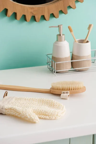 Productos de higiene en el estante cerca del cepillo de masaje y el guante de baño en el baño, concepto de cero residuos - foto de stock