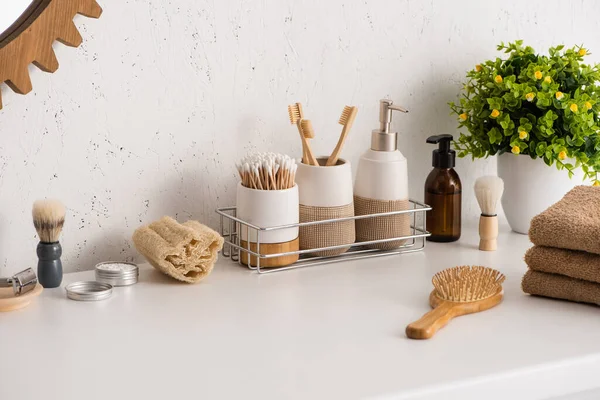 Estante con objetos de higiene y productos de belleza con maceta en el baño, concepto de cero residuos - foto de stock