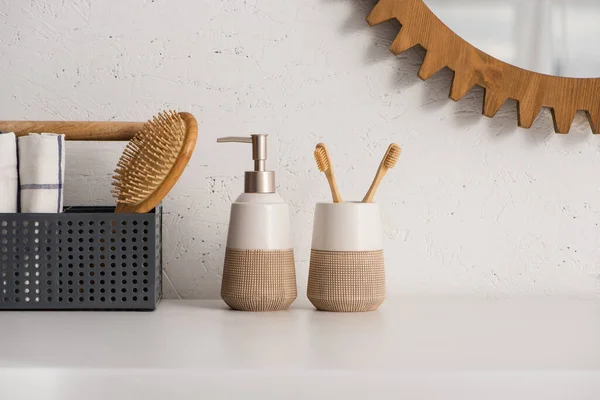 Caja con cepillo de pelo y toallas cerca de jabón líquido y soporte de cepillo de dientes con cepillos de dientes en el baño, concepto de cero residuos - foto de stock