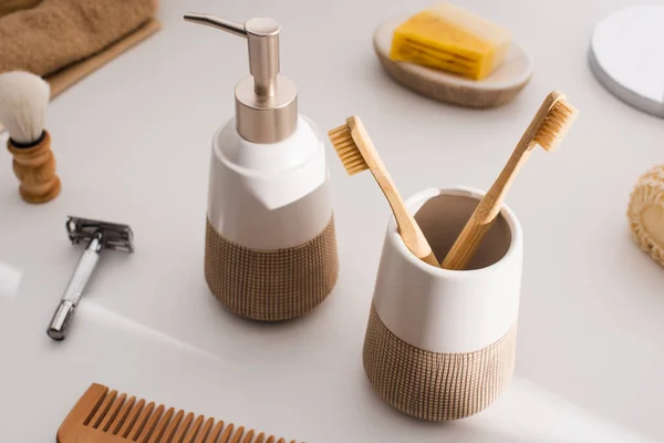 Close up view of liquid soap, toothbrush holder with toothbrushes and hygiene objects on grey, zero waste concept — Stock Photo