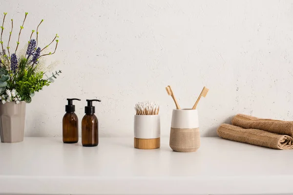 Flowerpot, eco body cream, toothbrush holders with hygiene objects and towels in bathroom, zero waste concept — Stock Photo