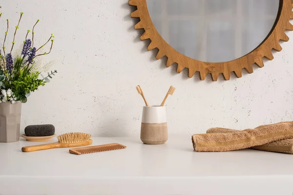 Maceta, toallas y objetos de higiene ecológicos cerca del espejo en la pared en el baño, concepto de cero residuos - foto de stock