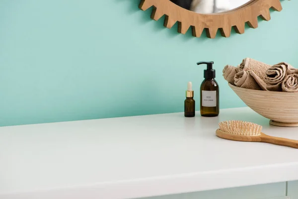 Расческа, бутылки эко крема для тела и масла, миска с полотенцами возле зеркала в ванной комнате, нулевая концепция отходов — стоковое фото