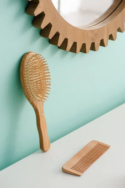 Hairbrush with comb and round mirror on turquoise wall in bathroom, zero waste concept — Stock Photo