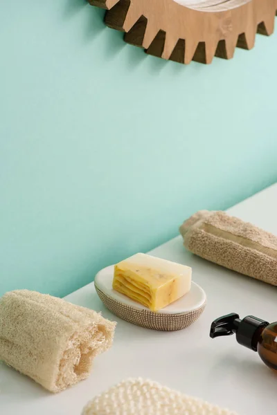 Enfoque selectivo de loofah, botella de crema corporal ecológica, jabón y toalla en el baño, concepto de cero residuos - foto de stock