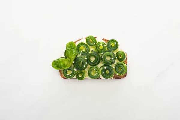 Вид зверху на свіжий тост з огірком з листям базиліка на білому тлі — стокове фото