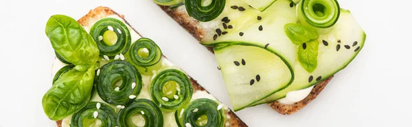 Vista superior de tostadas de pepino fresco con semillas y hojas de albahaca aisladas en blanco, plano panorámico - foto de stock