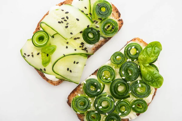 Vista superior de torradas de pepino fresco com sementes e folhas de manjericão isoladas em branco — Fotografia de Stock