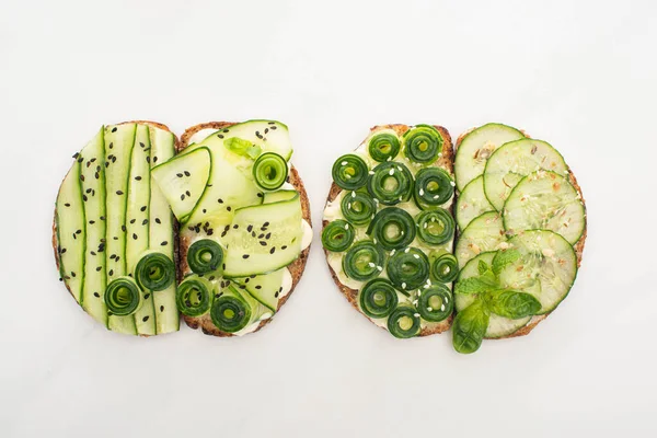 Vista dall'alto di toast di cetrioli freschi con semi, menta e foglie di basilico su sfondo bianco — Foto stock