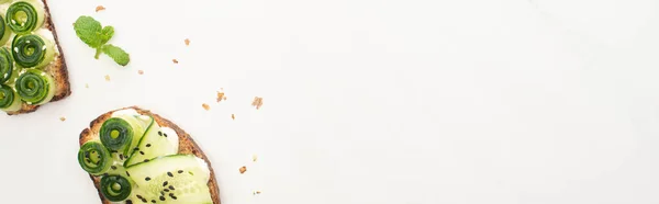 Top view of fresh cucumber toasts with seeds, mint on white background, panoramic shot — Stock Photo