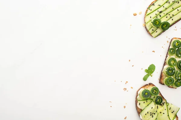 Draufsicht auf frische Gurken-Toasts mit Samen, Minze auf weißem Hintergrund — Stockfoto