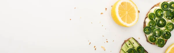 Vista superior de torradas de pepino fresco com sementes perto de limão no fundo branco, tiro panorâmico — Fotografia de Stock