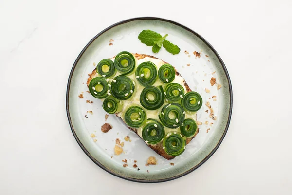 Top view of fresh cucumber toast with sesame and mint leaves on plate on white background — Stock Photo