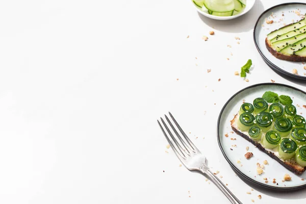 Fresh cucumber toasts on plates near fork on white background — Stock Photo