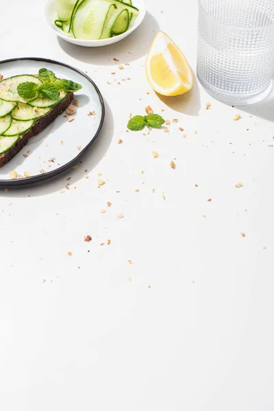 Frischer Gurkentoast mit Samen, serviert mit Zitrone und Wasser auf weißem Hintergrund — Stockfoto