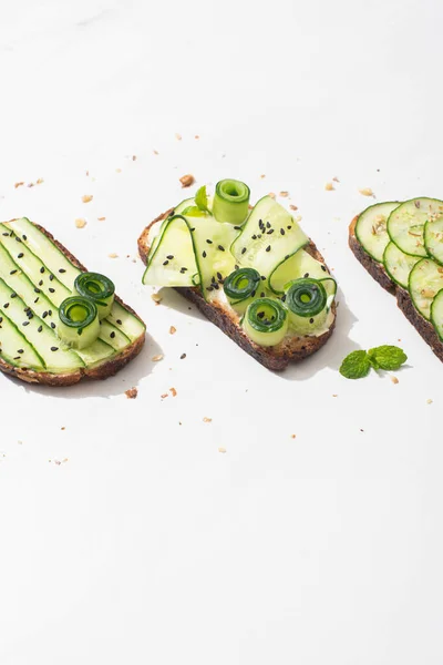 Frische Gurken-Toasts mit Samen, Minzblätter auf weißem Hintergrund — Stockfoto