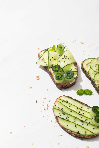 Torradas de pepino fresco com sementes, folhas de hortelã no fundo branco — Fotografia de Stock