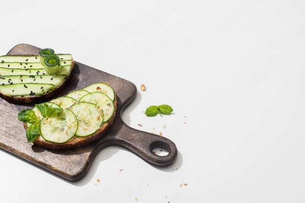 Fresh cucumber toasts on wooden cutting board on white background — Stock Photo