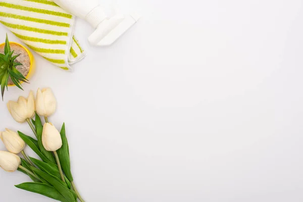 Top view of spring tulips and houseplant near cleaning supplies on white background — Stock Photo